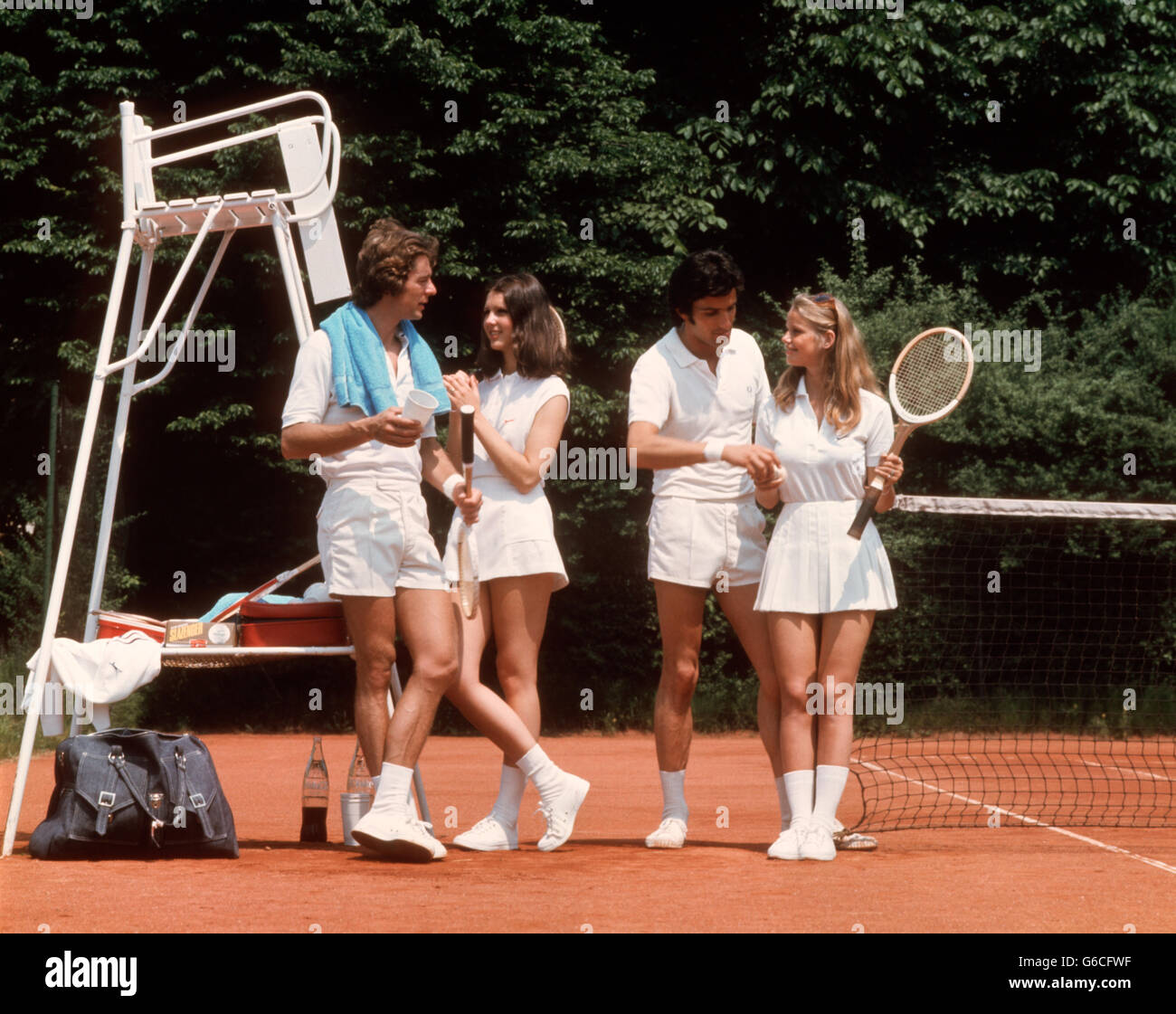 1970S 1980S PAARE ZWEI TRAGEN WEIßE TENNISBEKLEIDUNG STANDING ON COURT WEITER ANS NETZ Stockfoto
