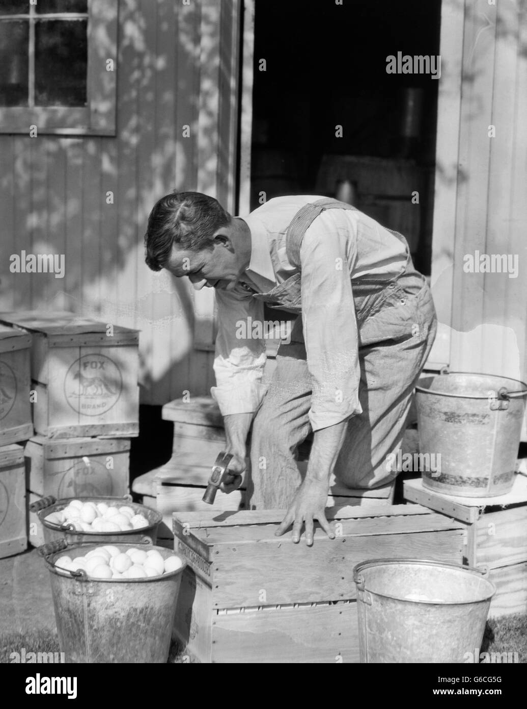 1920S 1930S MANN BAUER TRAGEN LATZHOSE NAGELUNG GESCHLOSSEN AUS HOLZ VERSAND KISTEN EIER Stockfoto