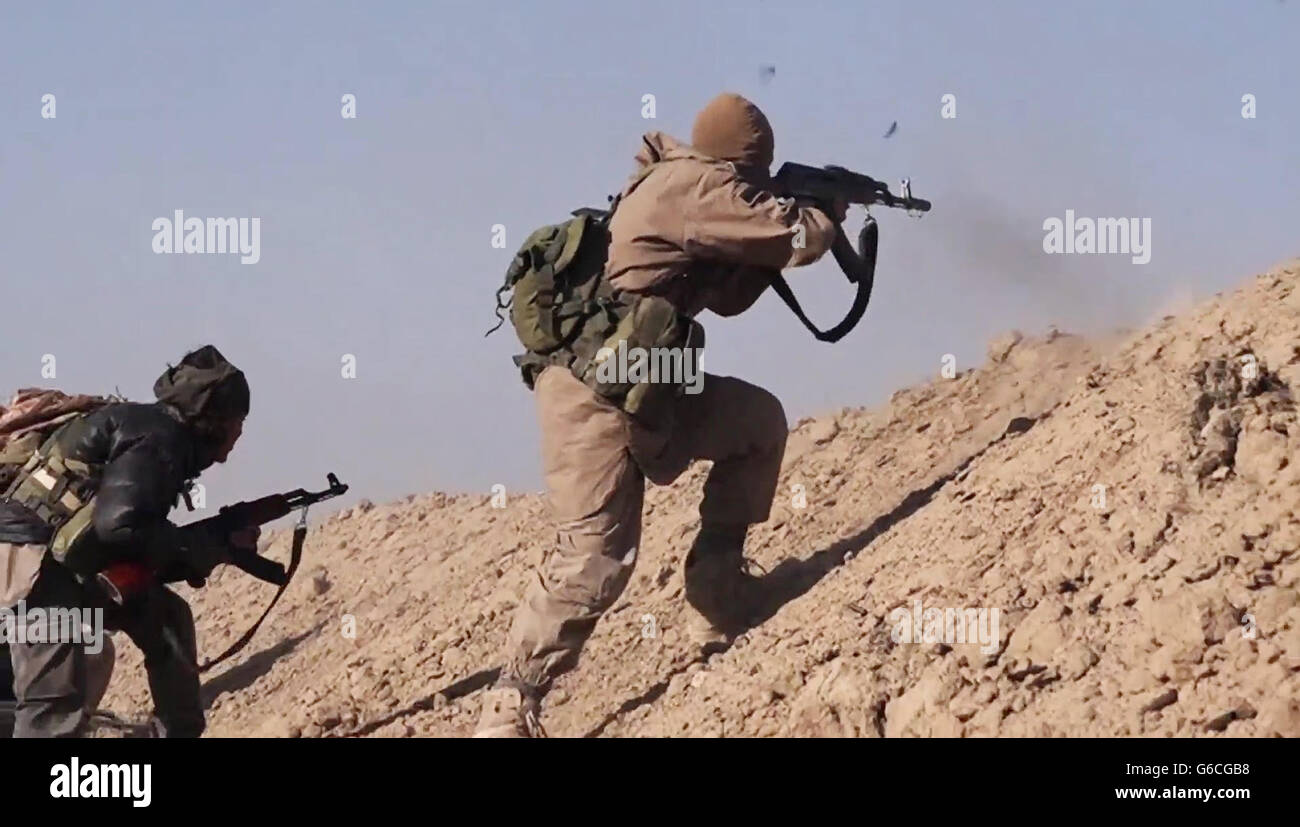 Islamischer Staat Kämpfer Feuer AK-47 Gewehre bei kämpfen in den Bergen Makhoul 30. Mai 2016 in der Nähe von Baiji, Irak. Das Standbild wird aus einem Propaganda video veröffentlicht von der islamischen Staates im Irak und der Levante erfasst. Stockfoto