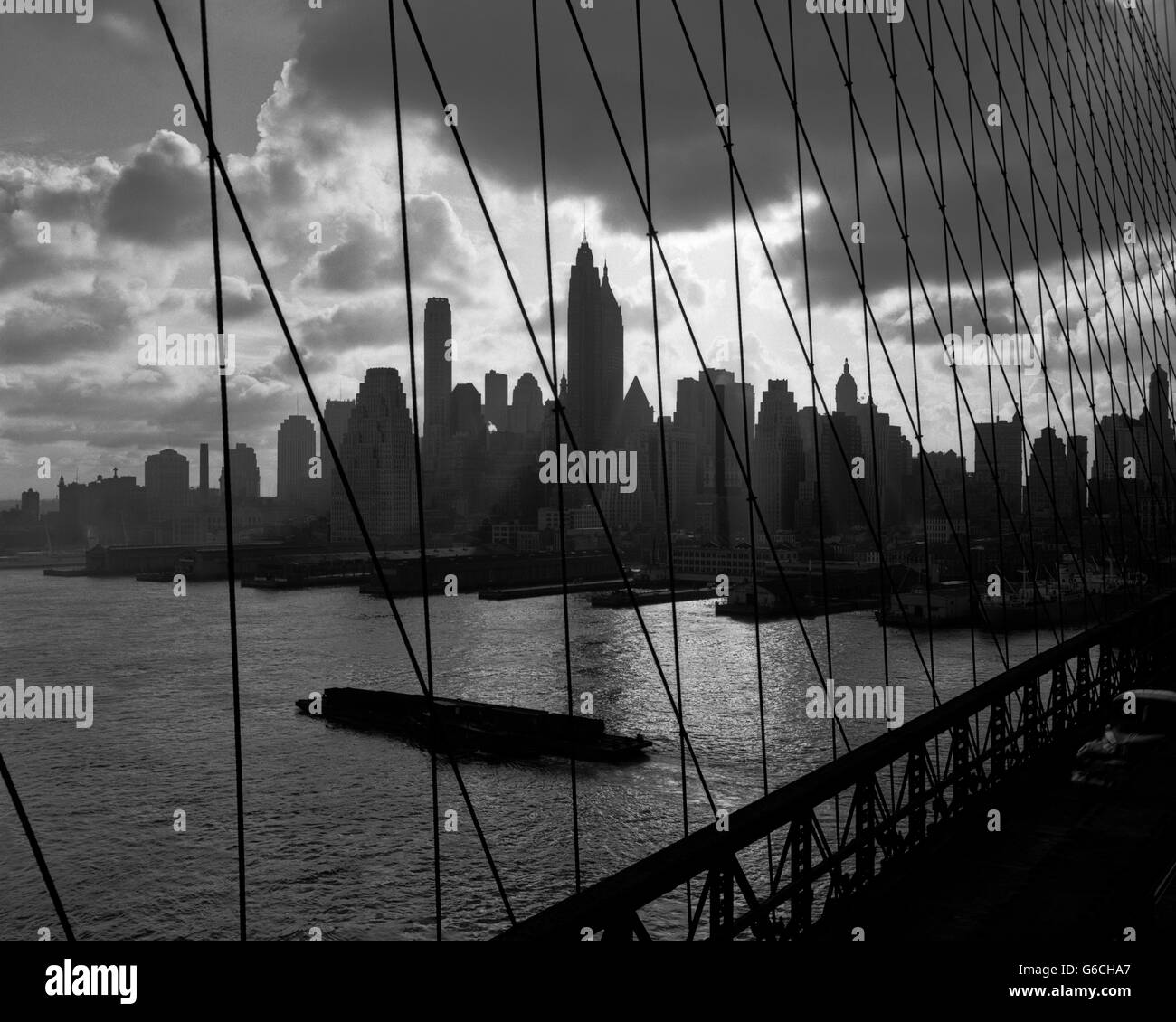 1950S 1960S DOWNTOWN MANHATTAN SKYLINE VON BROOKLYN BRIDGE BARGE IM EAST RIVER-NEW YORK-USA Stockfoto