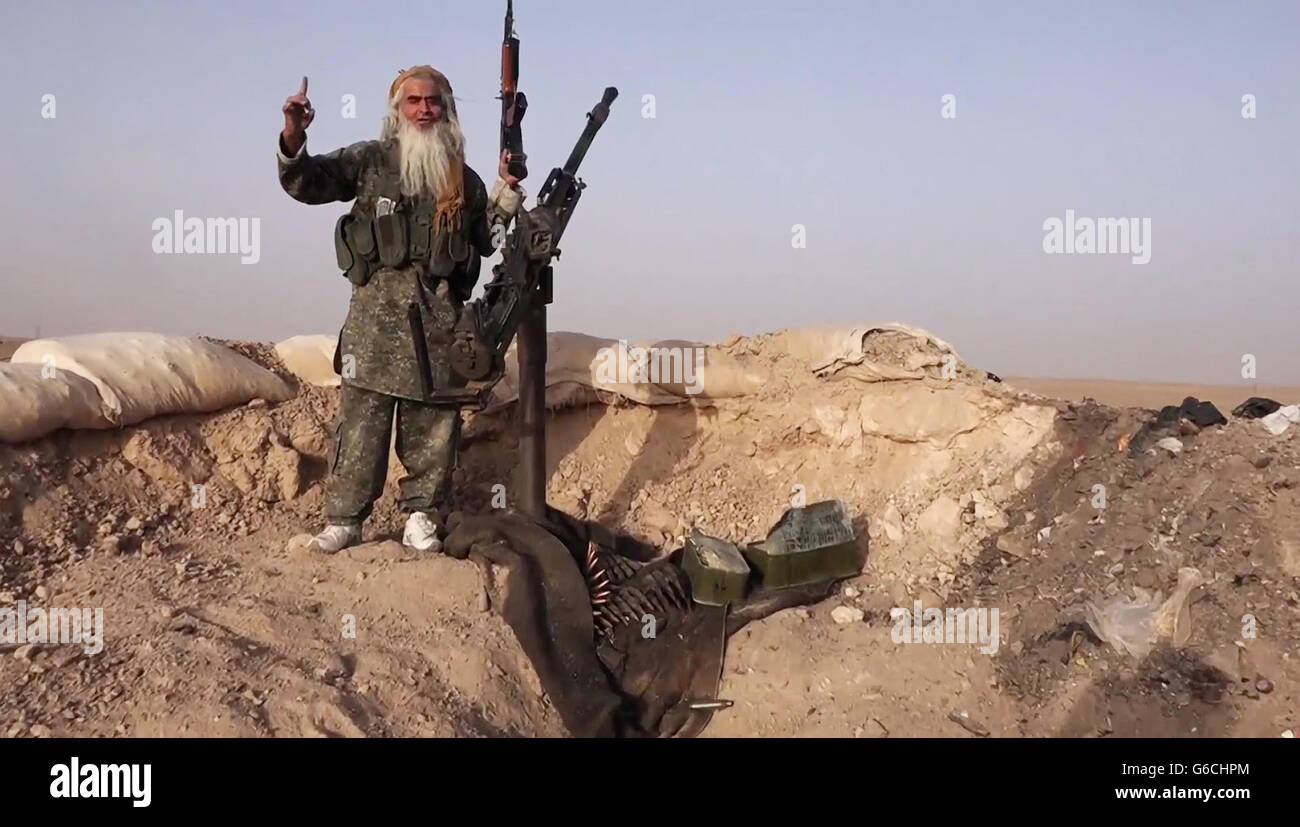 Eine ältere islamischer Staat Kämpfer stellt mit einer Gefangenen KPV-Kanone nach über laufende Vorposten bei kämpfen in den Bergen Makhoul 30. Mai 2016 in der Nähe von Baiji, Irak. Das Standbild wird aus einem Propaganda video veröffentlicht von der islamischen Staates im Irak und der Levante erfasst. Stockfoto