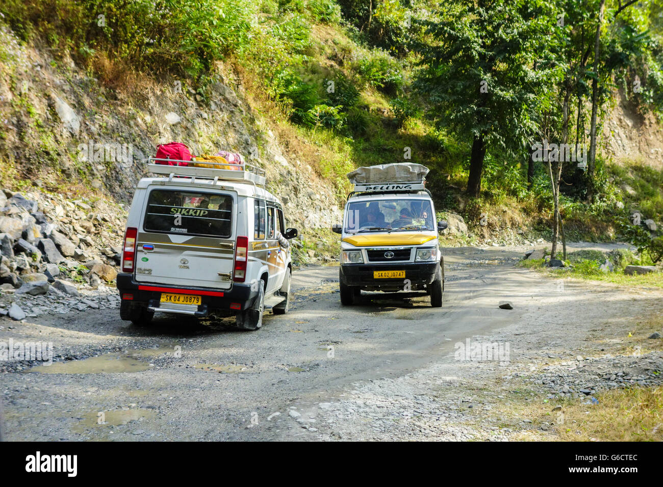 Zwei Touristenfahrzeuge Kreuz auf ein schlechtes Pflaster sumpfige, mucky Straße mit Schlaglöchern auf dem Weg zum Pelling in Sikkim von Darjeeling Stockfoto