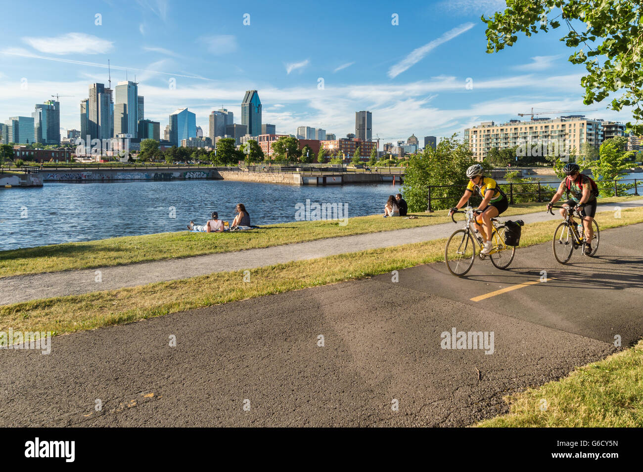 Menschen auf Fahrrädern auf Lachine Canal Radweg in Montreal, mit Skyline im Hintergrund. Stockfoto