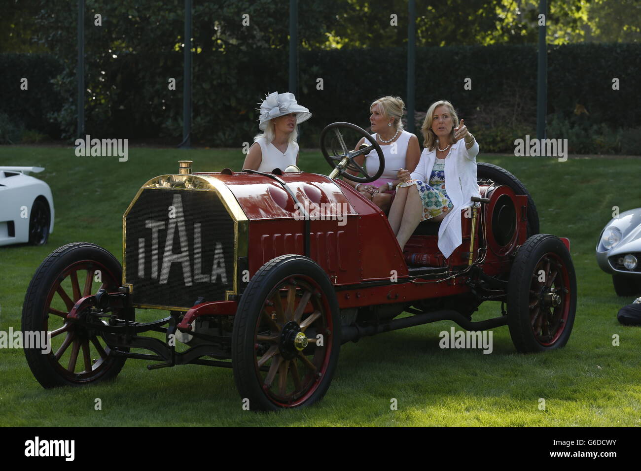 Besucher plaudern, während sie in einem 1907 Itala 120 ps starken Fahrzeug saßen, das im Rahmen der Eröffnung des St. James's Concours of Elegance Oldtimer-Events im Marlborough House Gardens, St. James's, London, ausgestellt wurde. Stockfoto