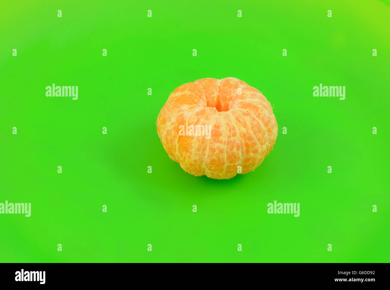 Geschälte Orange Clementine und Abschnitte über helle grüne Platte Stockfoto