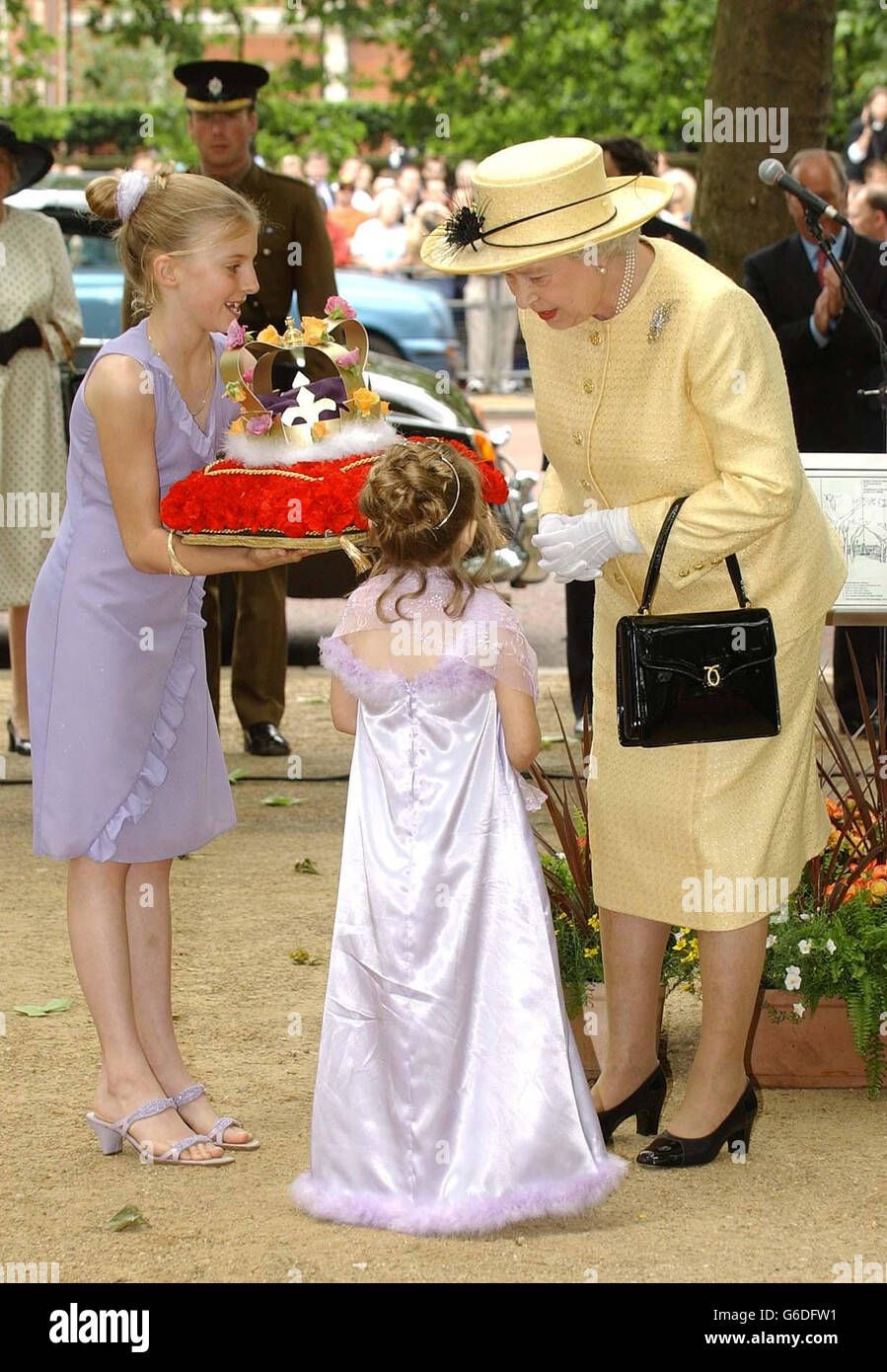 Die neunjährige Louisa Harrington aus Clevedon (Mitte), die unter Kardiomyopathie leidet, spricht in Begleitung ihrer Schwester Alice, 11, mit Königin Elizabeth II., bevor sie ihr eine Blumenkrone in der Londoner Mall übergibt, um den 50. Jahrestag ihrer Krönung zu feiern. Stockfoto