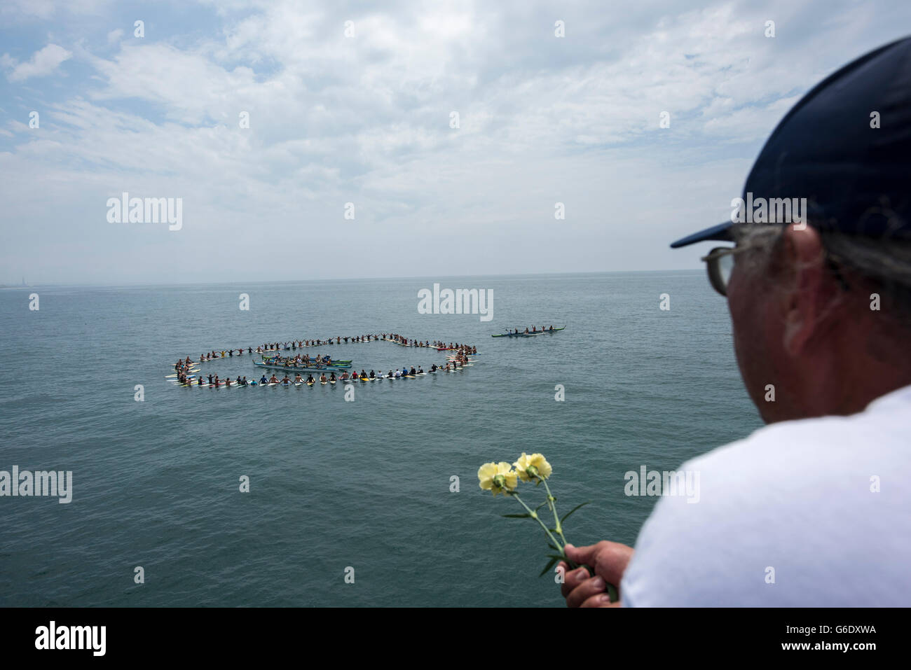 Ein Mann hält Blumen, wie er ausführt, eine Paddel zu Ehren lokaler Surf-Legende als Skydog im Oceanside Beach in Oceanside, Kalifornien, am 3. August 2014 bekannt. Stockfoto