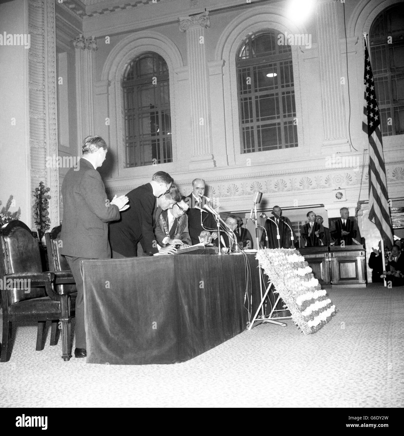 PRÄSIDENT JOHN F. KENNEDY von Amerika, wird applaudiert, als er das Besucherbuch im Rathaus unterschreibt, wo er während seines dreitägigen Besuchs in Irland die Freiheit der Stadt Cork erhielt. Mit ihm ist der Oberbürgermeister SEAN CASEY, in Roben und in einer Kette von Ämtern. Stockfoto