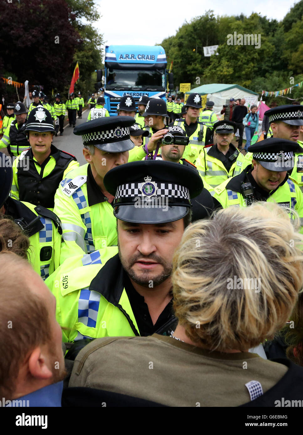 Polizeibeamte schieben Umweltaktivisten zurück, während sie einen Lastwagen verlangsamen, der zum Sondierungsbohrgebiet von Cuadrilla in Balcombe, West Sussex, fährt, während die Anti-Fracking-Demonstrationen fortgesetzt werden. Stockfoto