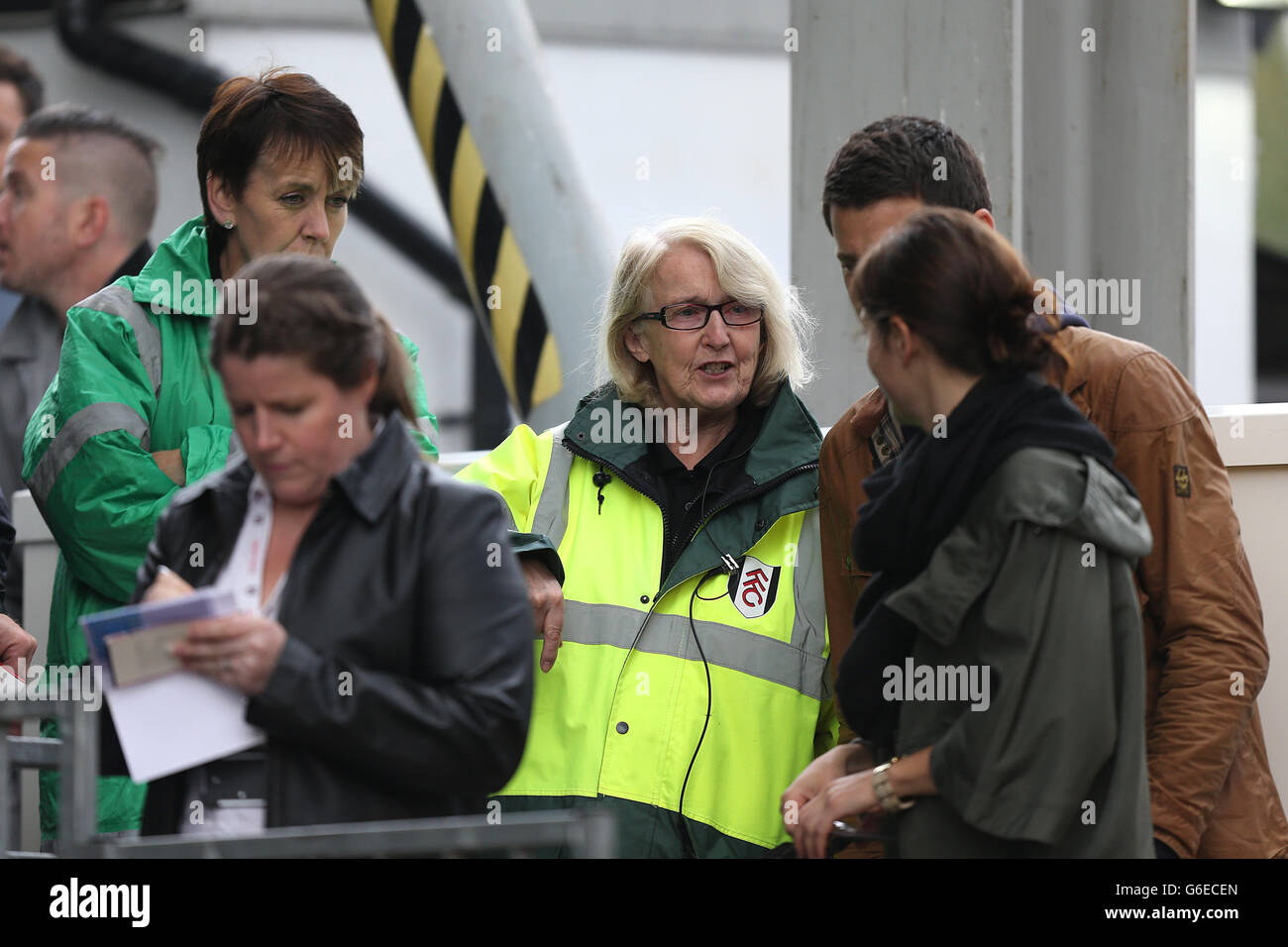 Ein Mitarbeiter von Fulham hilft Fans, vor dem Anpfiff ihren Platz zu finden Stockfoto