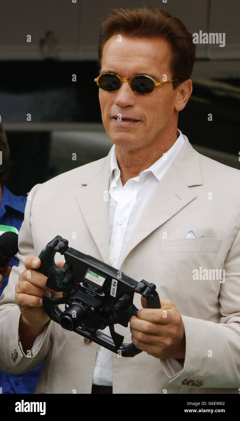 Arnold Schwarzenegger posiert mit einem Formel-1-Lenkrad beim British Grand Prix in Silverstone, Northamptonshire. *210703* Arnold Schwarzenegger. Zwölf Jahre nachdem er zuletzt den Terminator gespielt hatte, war Schwarzenegger am Montag, den 21. Juli 2003, zur Premiere des dritten Tranche wieder in der Stadt. Der 55-jährige Action-Held nimmt seine Rolle als Killer Cyborg in Terminator 3: Rise of the Machines wieder auf. Schwarzenegger und seine weiblichen Mitstars Kristanna Loken und Claire Danes sollten bei der UK-Premiere am Leicester Square in London auftreten. Stockfoto