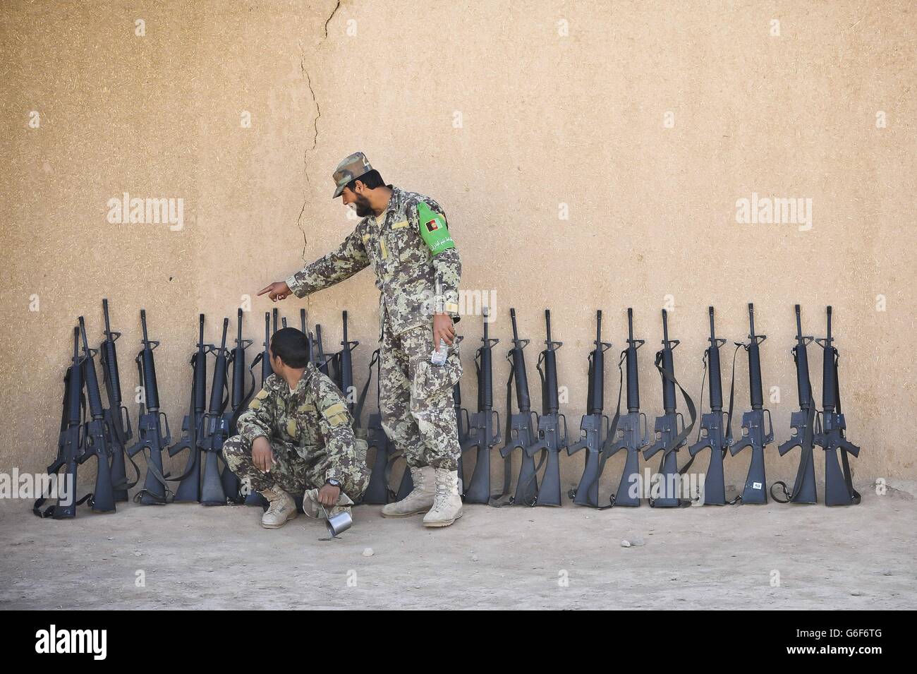 Soldaten der afghanischen Nationalarmee (ANA) stellen Waffen gegen eine Schlammmauer im ANA Camp Shorabak, Provinz Helmand, Afghanistan. Stockfoto