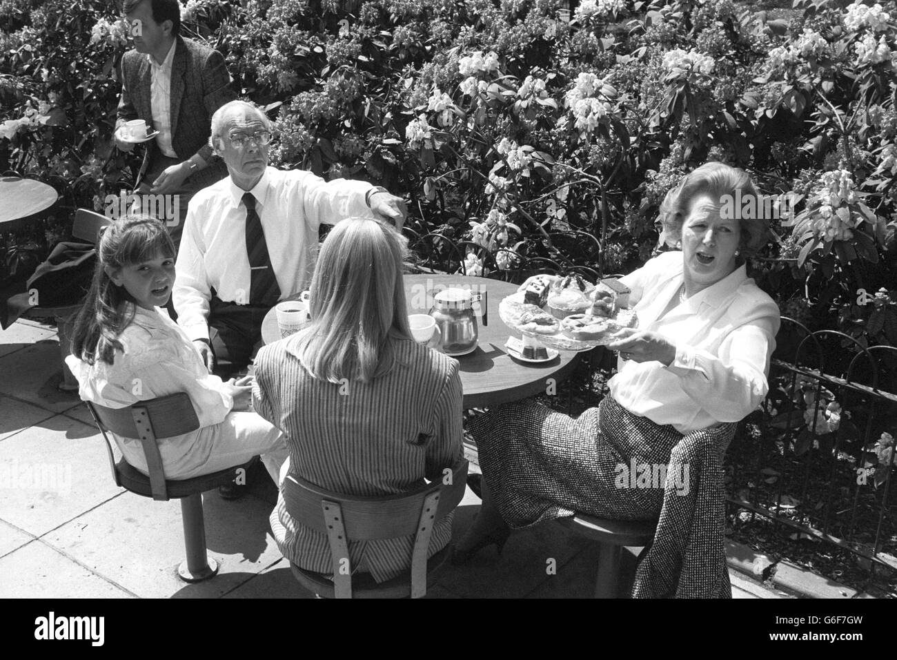 Premierminister Margaret Thatcher und Ehemann Denis bieten der Presse während einer spontanen Kaffeepause eine Auswahl an Kuchen an, wo sie sich in einem Café im St James's Park, London, mit überraschten Mitgliedern der Öffentlichkeit zusammentun. Stockfoto