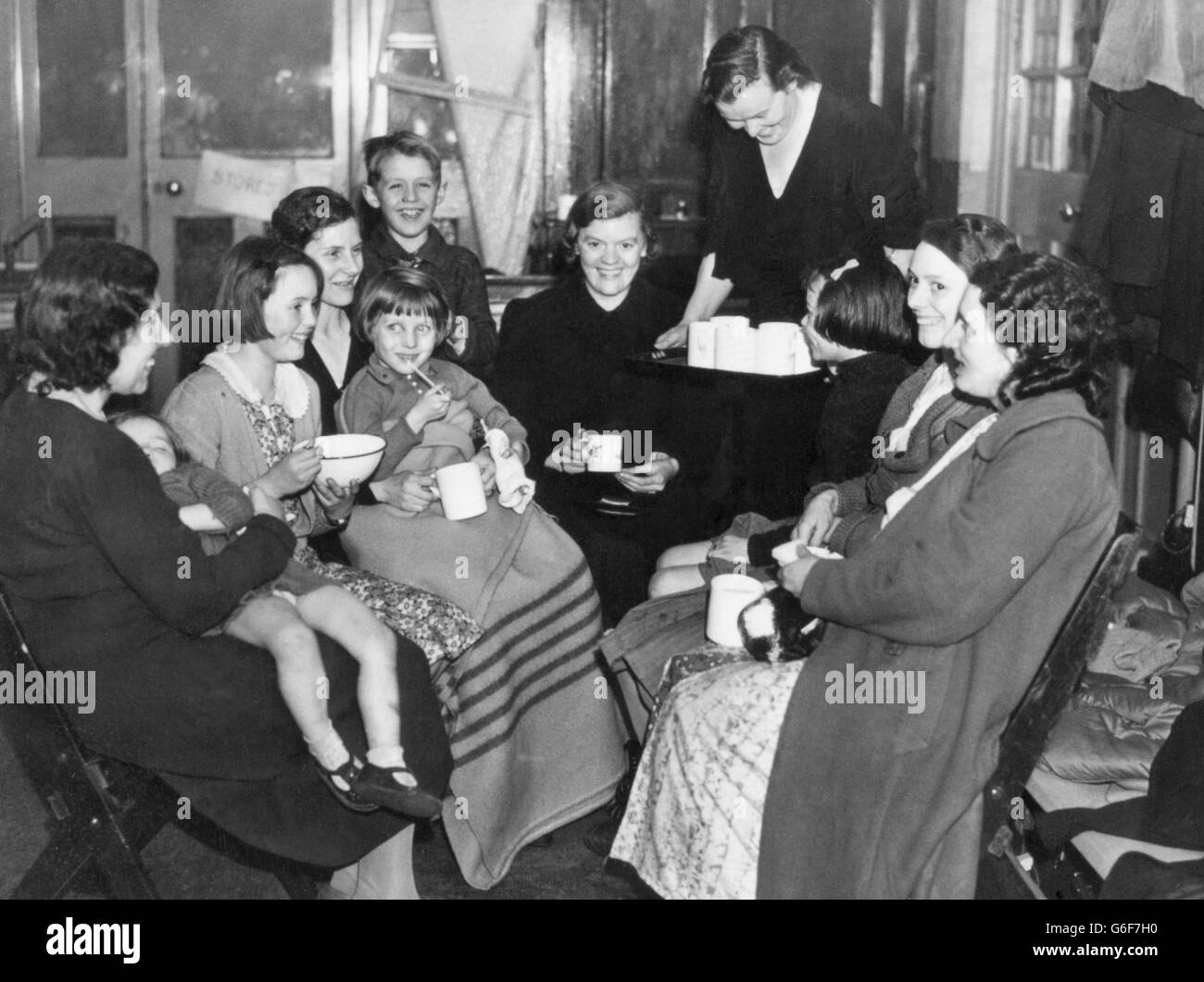 Eine Gruppe von Evakuierten im East End genießt Erfrischungen in ihren Notunterkünften, während sie auf eine neue Unterkunft warten. Stockfoto