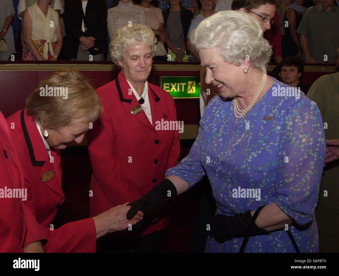 Die britische Königin Elizabeth II. Trifft die Royal Albert Hall-Stewardin Peggy Duffin (links) aus Bromley in Kent während der Pause des diesjährigen 17. BBC Prom, der in der Royal Albert Hall in London stattfand, während ihre Kollegin Christine Speckley (2. Links) aus Bradford in West Yorkshire auf sie schaut. Stockfoto