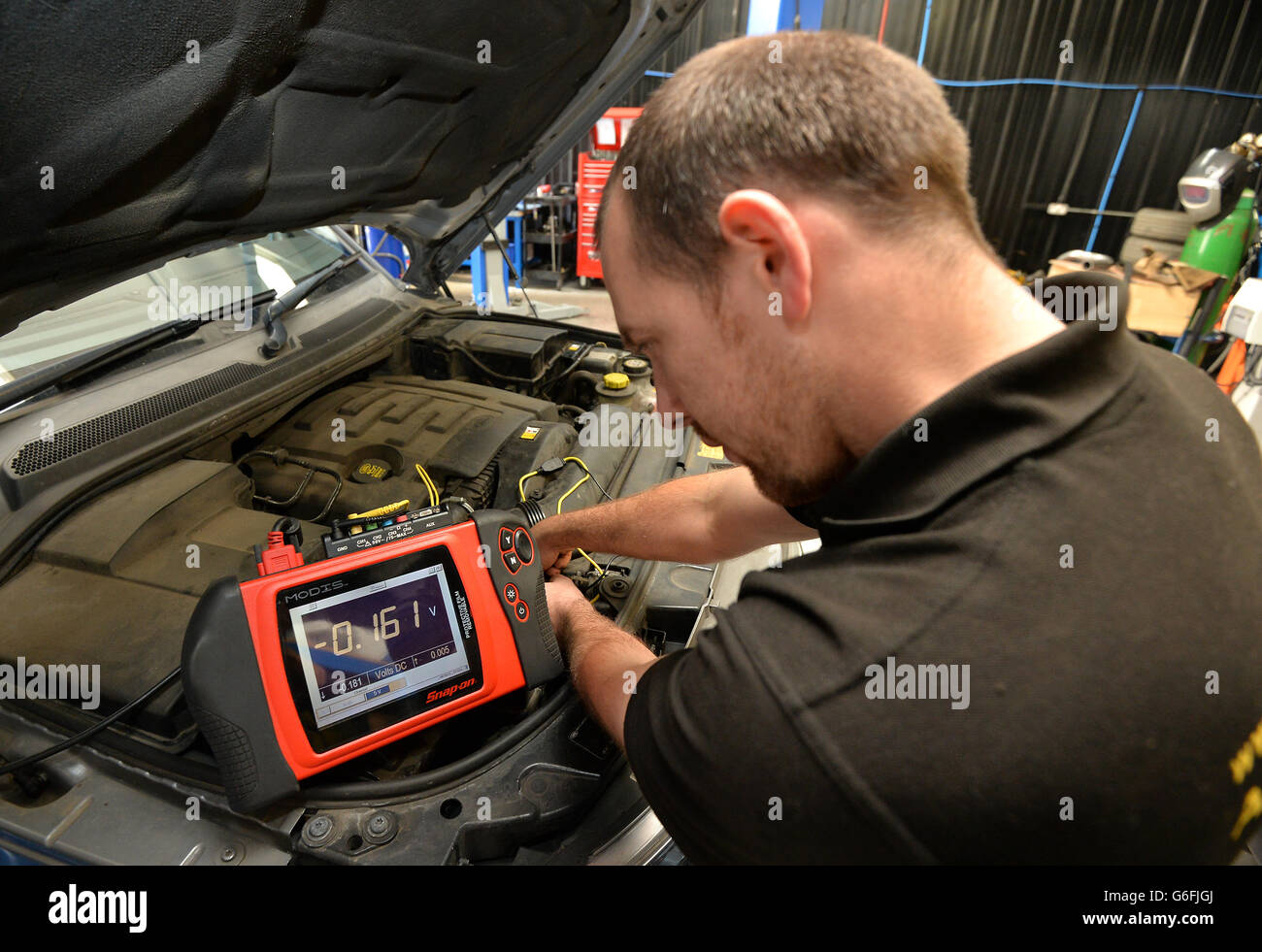 Ein Mechaniker verwendet ein modulares Diagnoseinformationssystem „Snap-on Modis“ Auf der Elektronik eines Autos Stockfoto