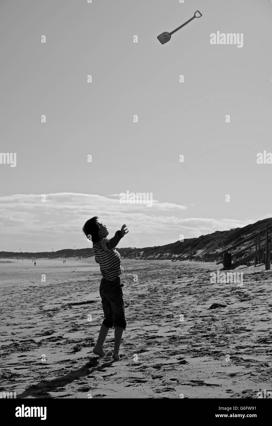 Junge werfen eine Schaufel am Strand Spaß haben Stockfoto