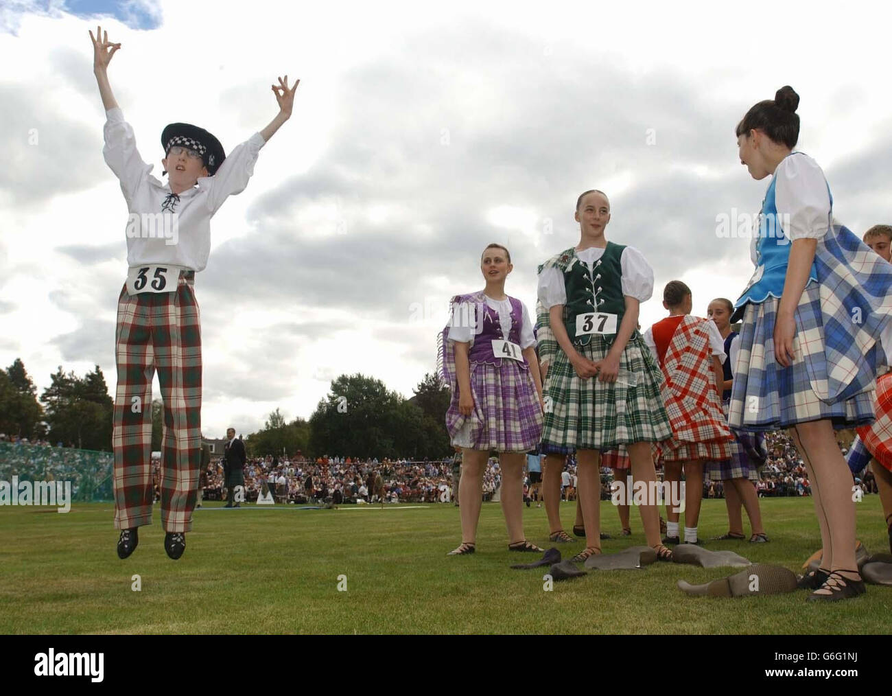 Callum zeigt den Mädchen, wie es bei den Braemar Royal Highland Games in Aberdeenshire gelungen ist. Die britische Königin Elizabeth und der Herzog von Edinburgh wurden von Premierminister Tony Blair und Frau Cherie begleitet, um die jährliche Veranstaltung zu verfolgen. .. Die eine Geschichte hat, die bis in die Tage von König Malcolm Canmore vor 900 Jahren zurückreicht. Stockfoto