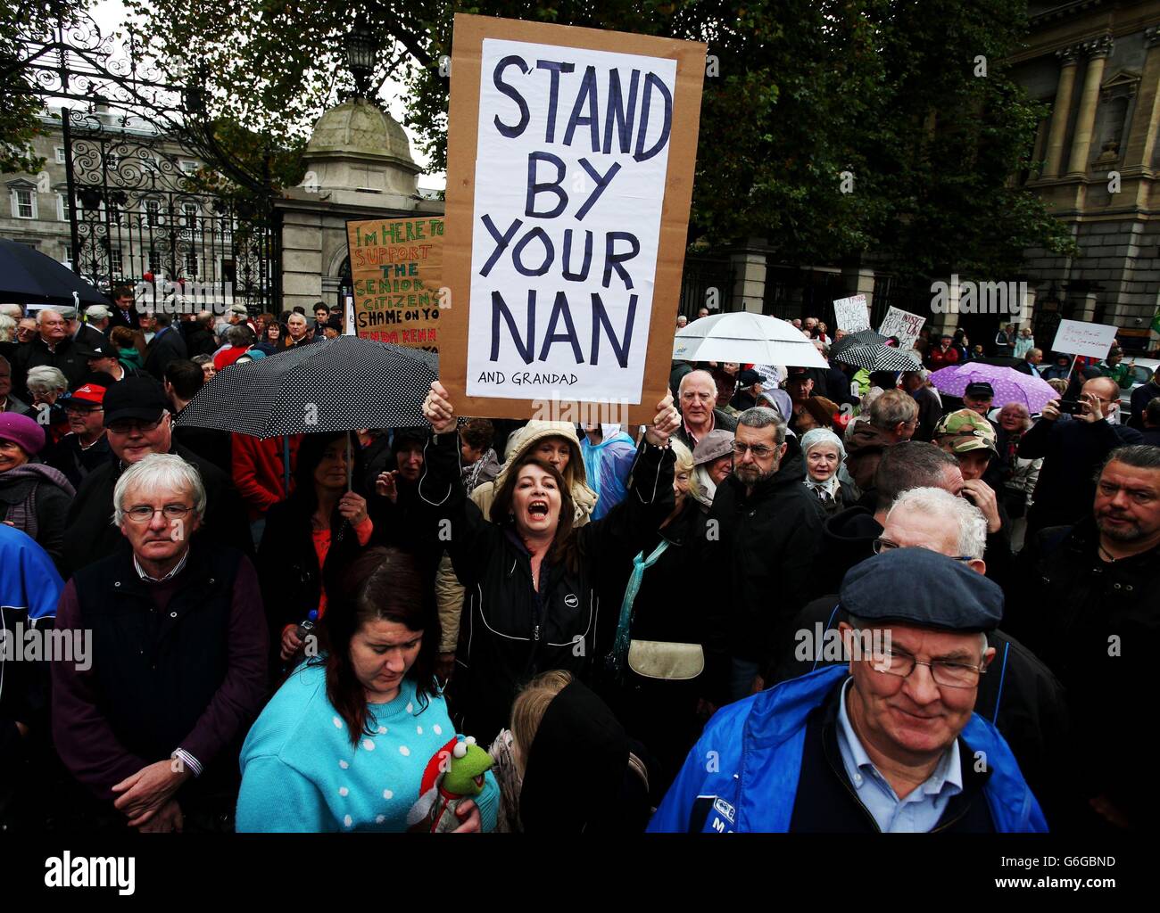 Eine Frau hält ein Schild während eines Protestes von Rentnern, vor Leinster House, Dublin, in Reaktion auf Budget 2014. Stockfoto