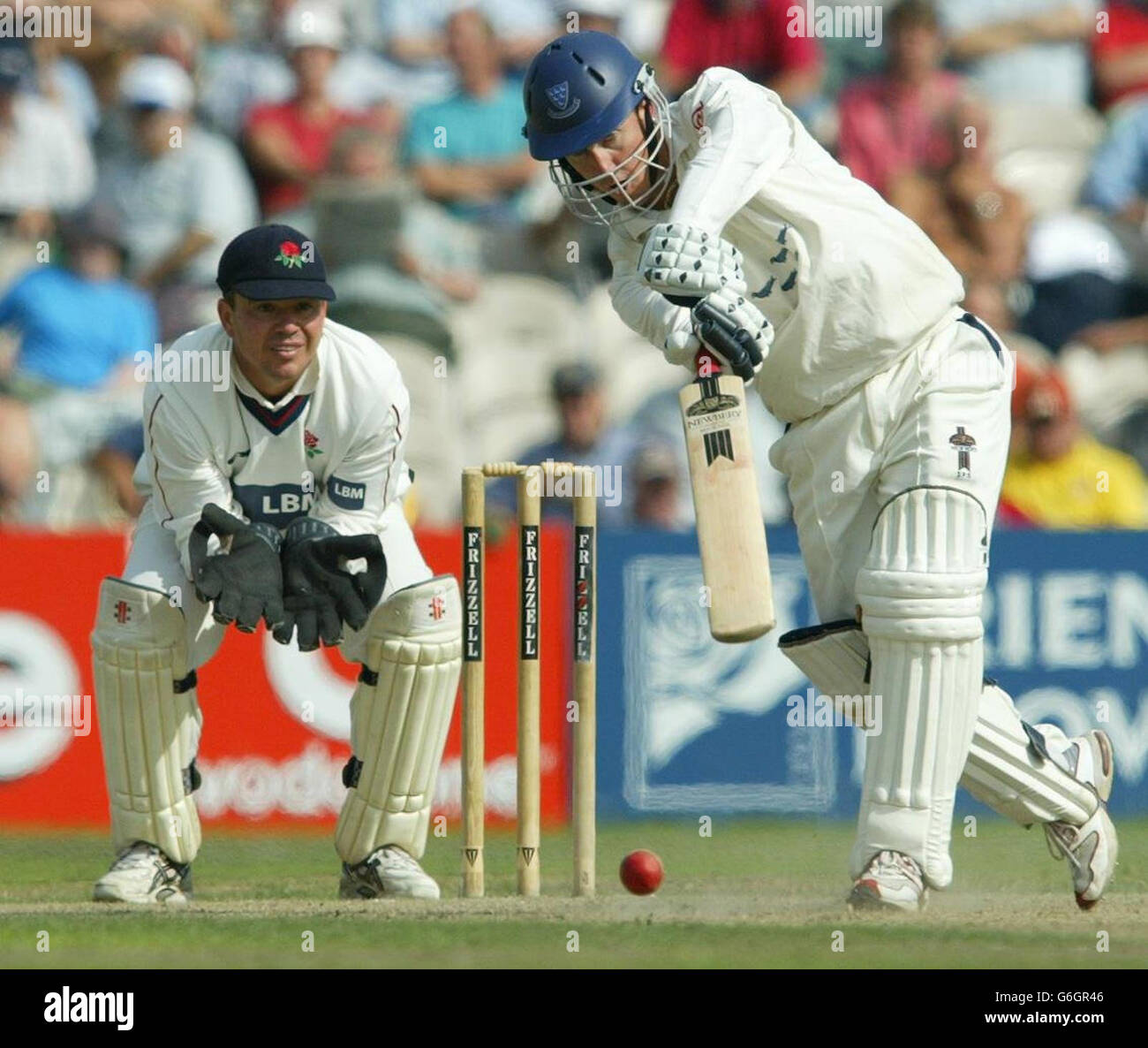 Sussex-Schlagmann Muray Goodwin fährt eine Lieferung von Gary Keedy aus Lancashire, während Warren Hegg während des Frizzell County Championship-Spiels in Old Trafford, Manchester, ansieht. Stockfoto