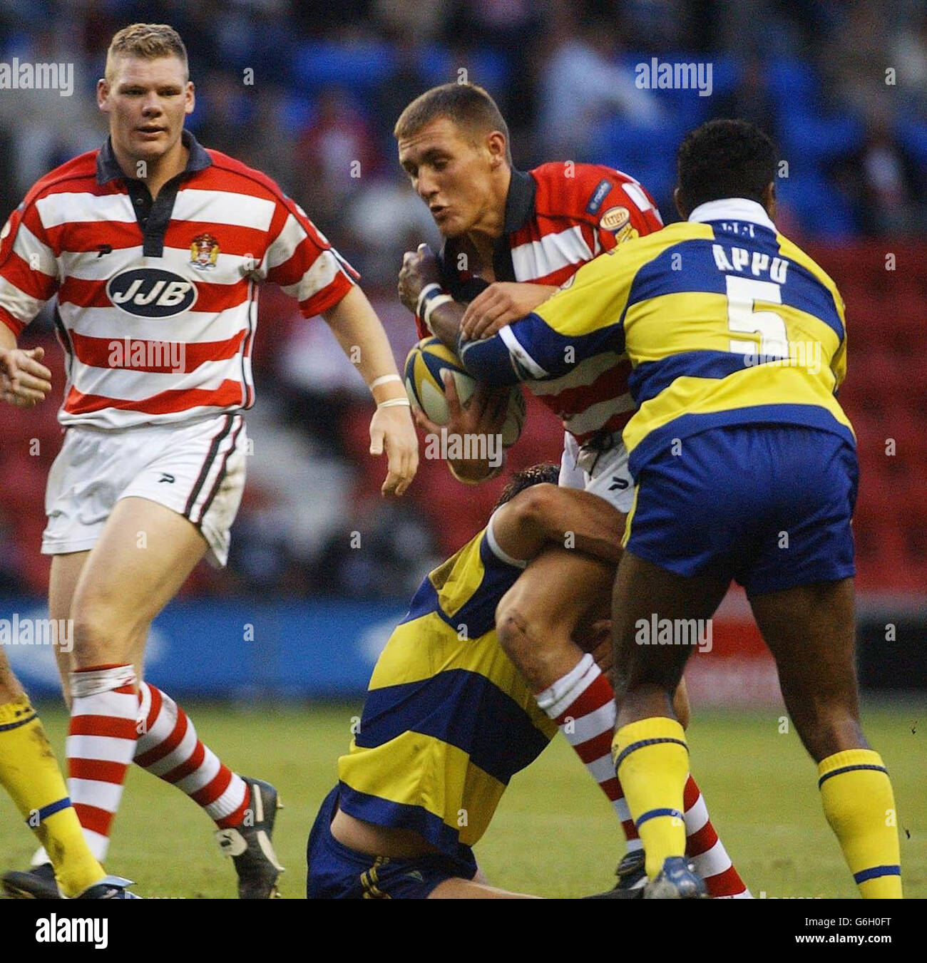 Wigan / Warrington. Gareth Hock von Wigan wird von der Warrington-Verteidigung während des Tetley's Super League-Spiels im JJB Stadium, Wigan, angegriffen. Stockfoto