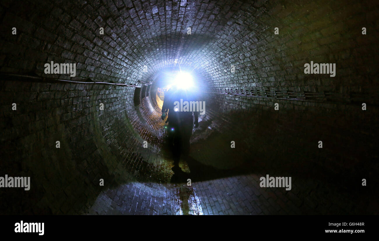 Ein Ingenieur geht durch das viktorianische Kanalsystem unterhalb von Brighton, East Sussex, während Southern Water die neuen £300 Millionen fassenden Abwasserbehandlungsarbeiten in Peacehaven nahe der Stadt eröffnet, die 11 km neuen Kanaltunnels, zwei Pumpstationen und einen 2,5 km langen Meeresausbruch umfassen. Stockfoto