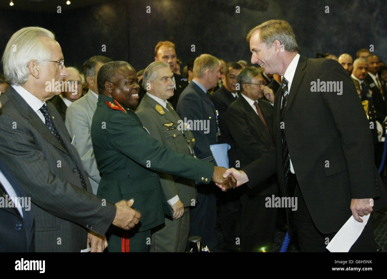 Der britische Verteidigungsminister Geoff Hoon begrüßt Delegierte, die an der internationalen Konferenz von Defense Systems & and Equipment 2003 teilnehmen, einer Waffenmesse, die in den Londoner Docklands stattfindet. Die Konferenz, die größte Waffenmesse in Europa. Stockfoto