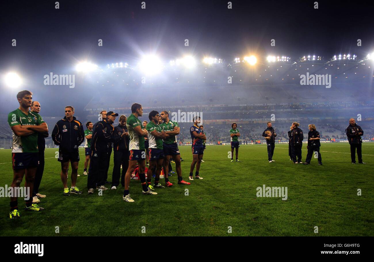 Australische Spieler und Hinterzimmer-Mitarbeiter sehen sich an, wie die irischen Spieler den Pokal im Spiel der International Rules Series im Croke Park, Dublin, Irland, heben. Stockfoto