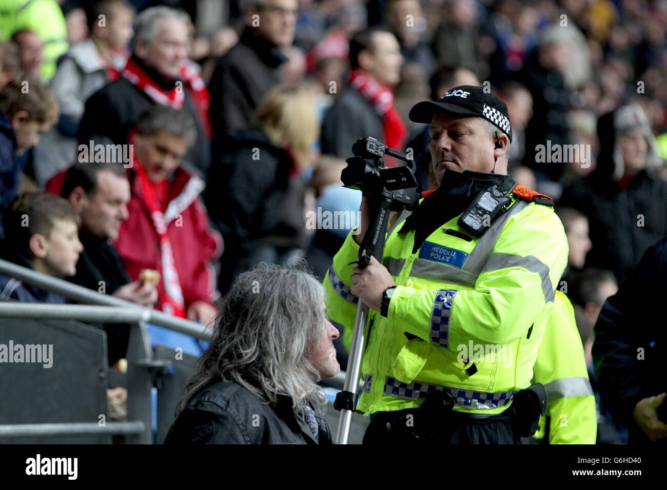 Fußball - Barclays Premier League - Cardiff City / Swansea City - Cardiff City Stadium. Ein Polizeibeamter filmt Fußballfans auf den Tribünen Stockfoto