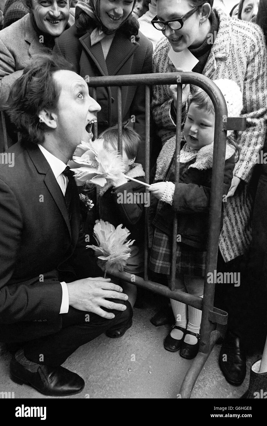 Ein Kind kitzelt Ken Dodd unter dem Kinn mit einem „Doddy Stick“, einem Federstaub, während der Eröffnung einer neuen Autodienststelle in Manchester. Stockfoto