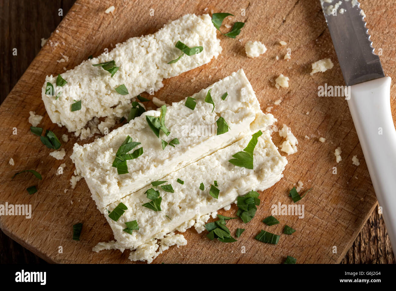 Frischkäse-Scheiben auf einem hölzernen Hintergrund mit Petersilie Stockfoto