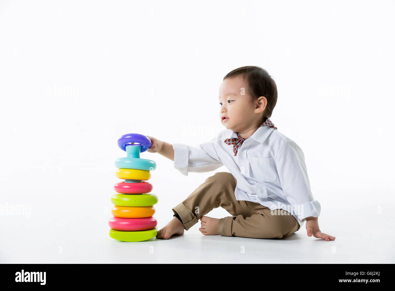 Kleine asiatische junge spielt mit Stapeln von bunten Ringe Spielzeug - Isolated on White Stockfoto