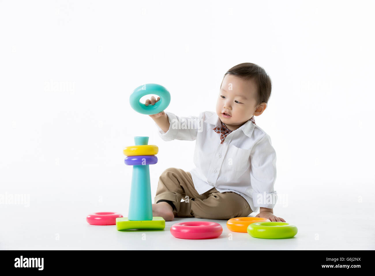 Kleine asiatische junge spielt mit Stapeln von bunten Ringe Spielzeug - Isolated on White Stockfoto