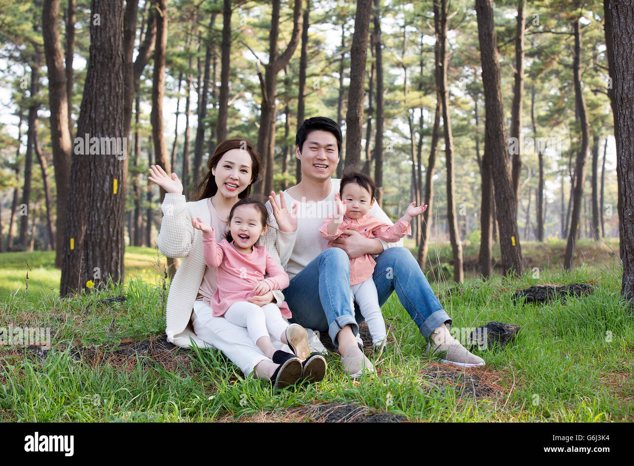 Glückliche asiatischen Familie sitzen auf dem Rasen, posiert im Wald Stockfoto