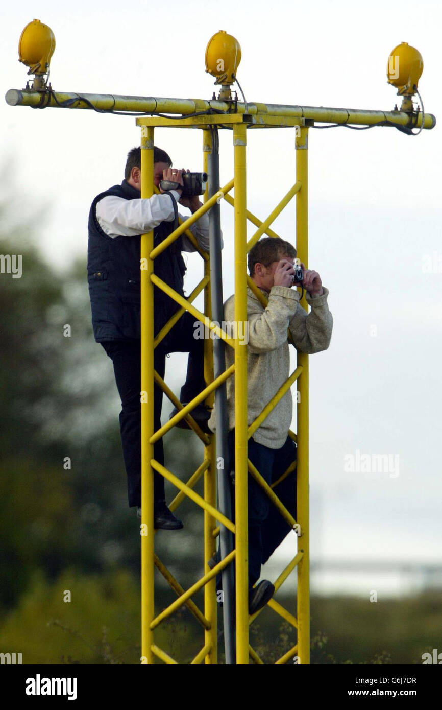 Zwei Flugzeugbeobachter klettern auf einen Lichtturm der Landebahn, um einen Blick auf die Concorde zu werfen, die den Flughafen Edinburgh verlässt. Stockfoto