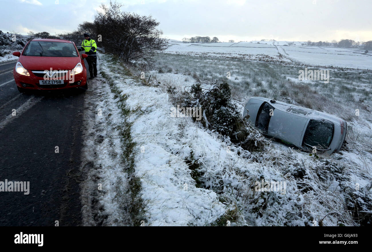 Ein Autofahrer hatte Glück, nachdem sein Auto die Straße in den Hügeln über Carnlough in Co Antrim verlassen hatte, als der erste Schneefall der Saison Teile der Provinz überzog, mit der Met-Büro Warnung vor Eis auf vielen Straßen heute Morgen, als die Temperaturen über Nacht fielen. Stockfoto