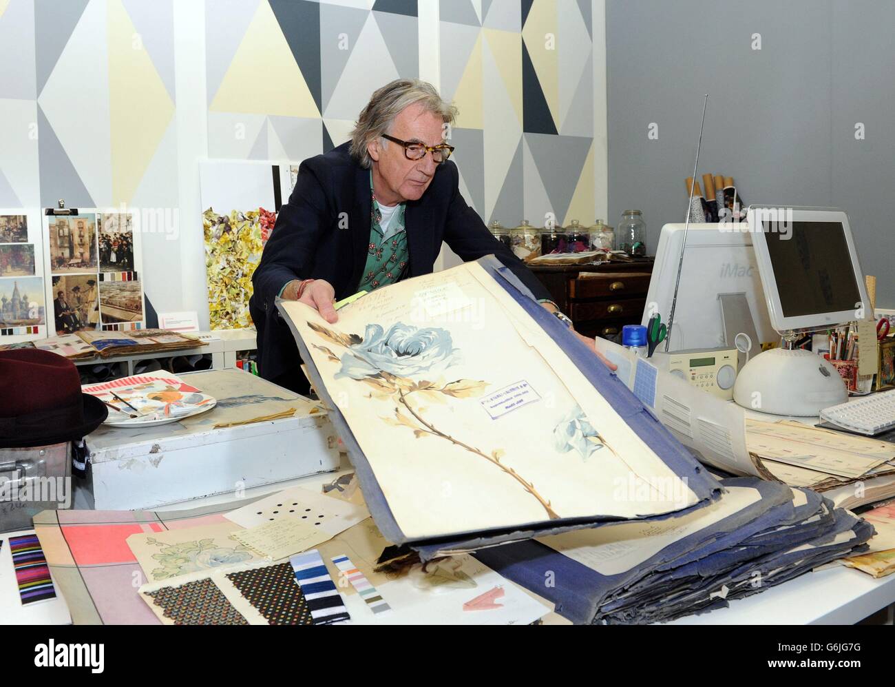 Der Modedesigner Paul Smith posiert bei der Eröffnung seiner neuen Ausstellung „Hello, My Name is Paul Smith“ im Design Museum, London, für Fotografien in einer Replik seines Arbeitsraums. Die Ausstellung zeigt Hunderte von Objekten aus dem persönlichen Archiv des Designers, darunter Fotografien, Objekte und viele seiner Kleidungsentwürfe aus seiner gesamten Karriere. Stockfoto