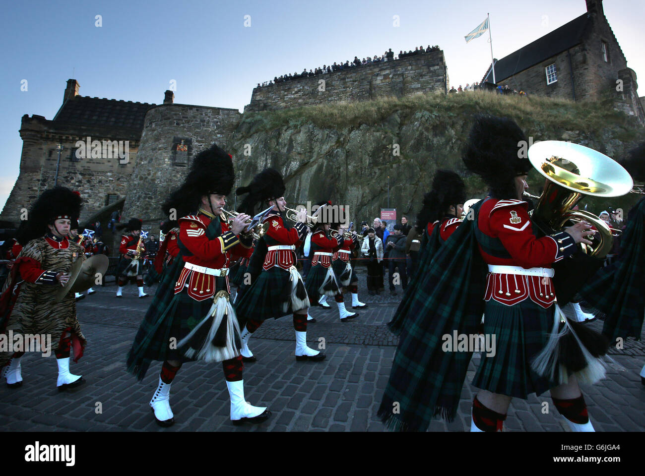 Die Military Band marschiert vorbei, als die schottischen Gunners der Royal Artillery anlässlich des 65. Geburtstages des Prinzen von Wales einen königlichen Gruß mit 21 Kanonen auf dem Edinburgh Castle abfeuern. Stockfoto