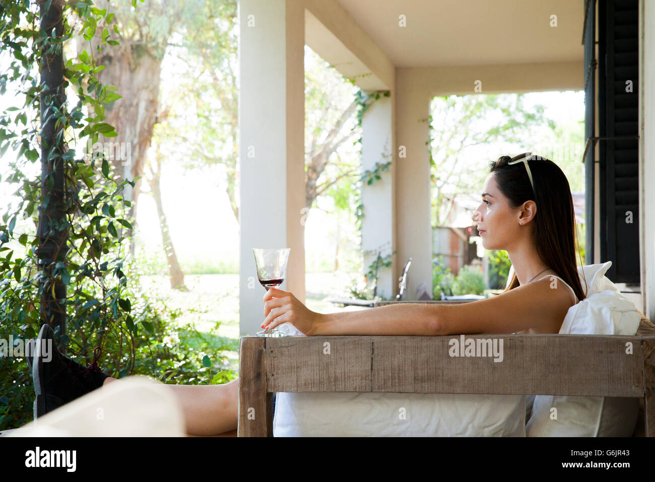 Frau entspannen auf der Veranda mit einem Glas Wein Stockfoto