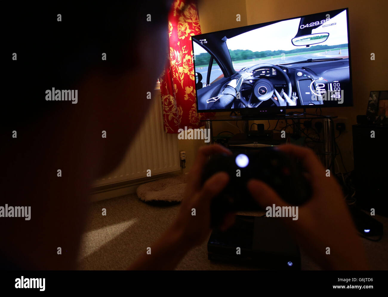 Ein Teenager hält einen Controller, um das Videospiel Forza Motorsport 5 auf einer Microsoft Xbox One Konsole zu spielen, in Corfe Mullen, Dorset. Stockfoto