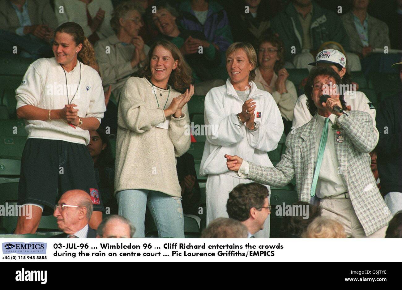 03-JUL-96. Wimbledon 96. Cliff Richard unterhält die Massen während des Regens auf dem Center Court (Martina Navratlova (bis l von Cliff)) Stockfoto
