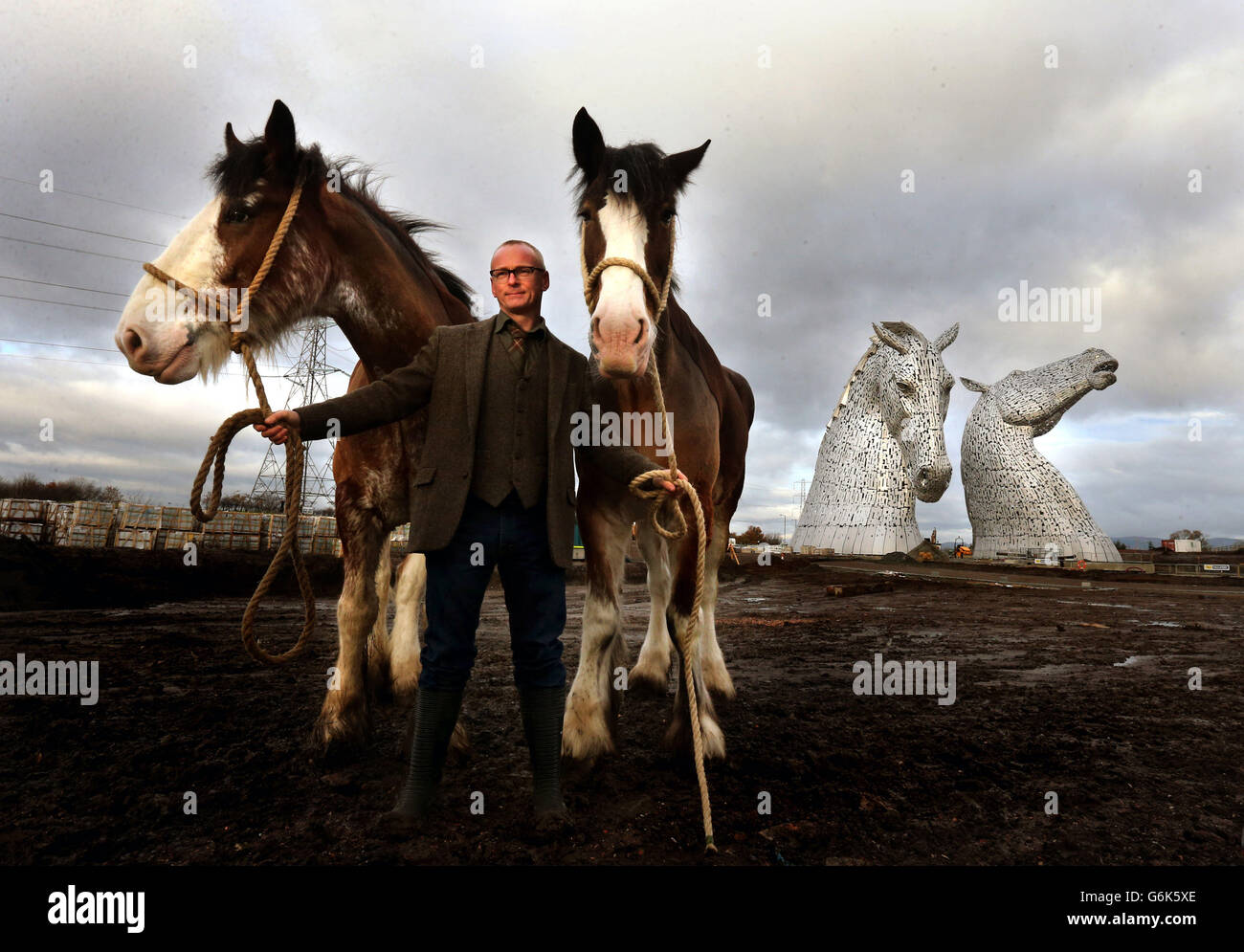 Der Künstler Andy Scott steht mit den Clydesdale Horses Duke (links) und Baron vor seinem Werk The Kelpies, das nach seiner Fertigstellung ein Tor zum Forth und Clyde Kanal am Helix, Falkirk, Schottland, bildet. Stockfoto