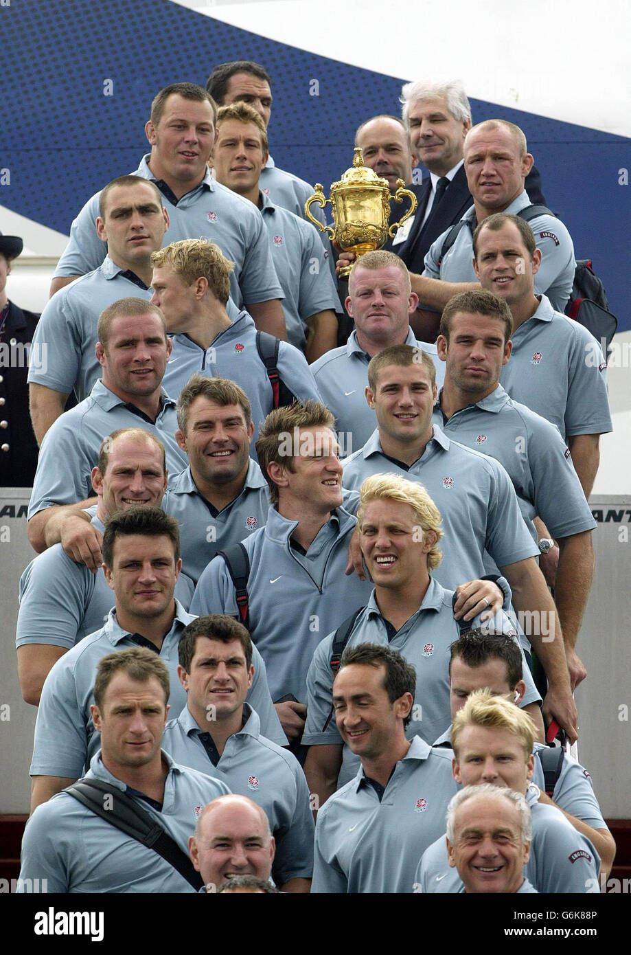 Die englische Rugby-Mannschaft posiert für ein Foto mit der WM am Sydney Airport, als sie das Flugzeug besteigen - umbenannt in Sweet Chariot - das sie zurück nach London bringt. Sie sollen in den frühen Morgenstunden des Dienstags in Heathrow ankommen. Stockfoto