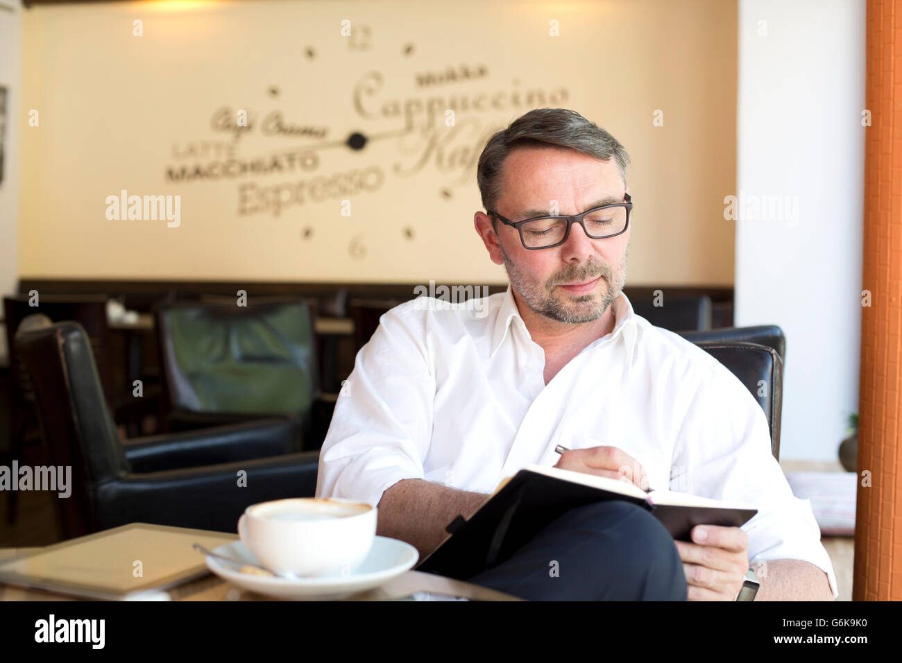 Porträt des Kaufmanns sitzen in einem Café mit Notebook etwas aufschreiben Stockfoto