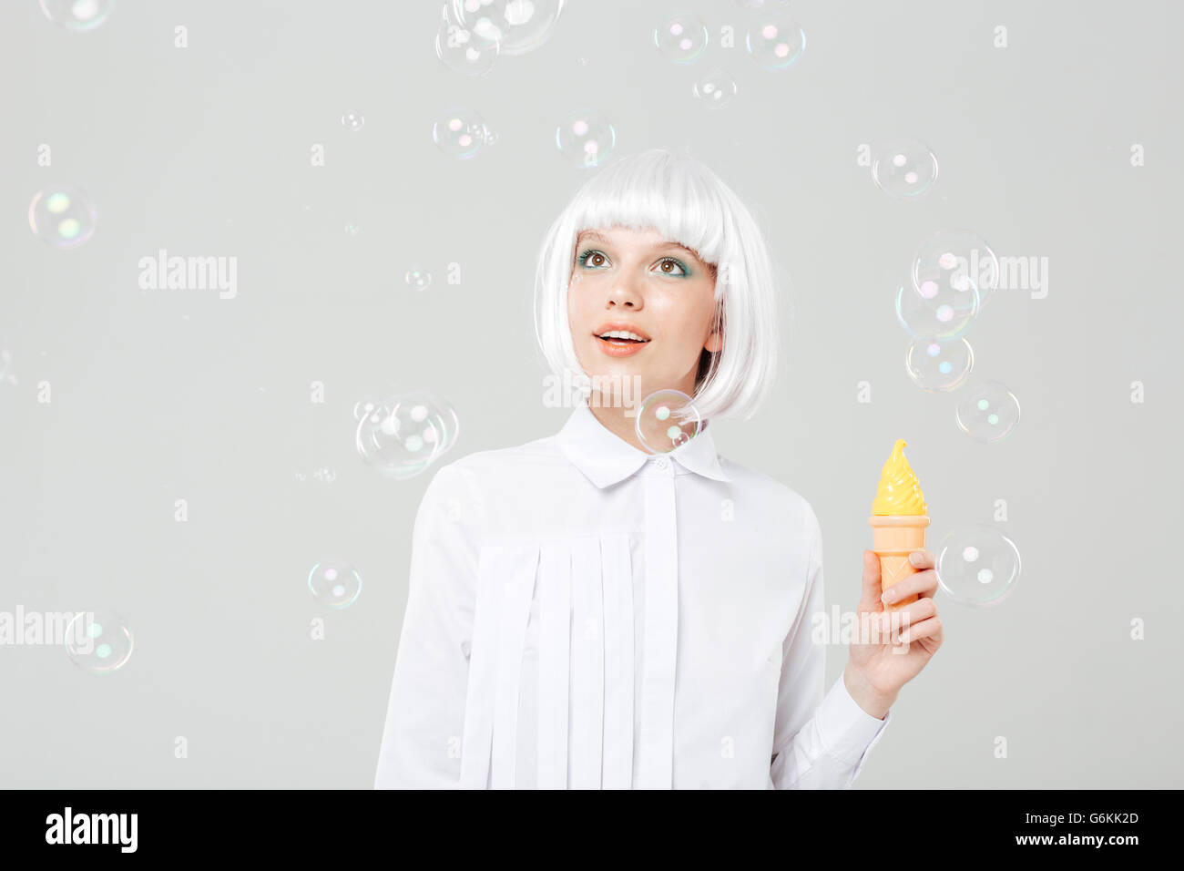 Glücklich süße junge Frau betrachten Seifenblasen und gefälschte Eis halten auf weißem Hintergrund Stockfoto