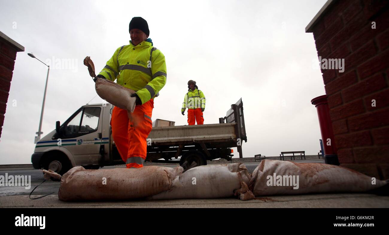 Mitarbeiter des Stadtrats von Denbyshire bauen auf den Pfaden zu Häusern an der Coast Road in Rhyl, Nordwales, Hochwasserschutzanlagen mit Sandsäcken, da die Gegend aufgrund von starken Winden und Gezeiten hochflutet. Stockfoto