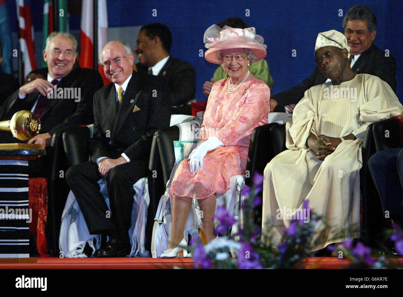 Erste Reihe von links - Commonwealth-Generalsekretär Don McKinnon, der australische Premierminister John Howard, die britische Königin Elizabeth II. Und der nigeranische Präsident Olusegun Obasanjo sehen traditionelle Tänze während einer Eröffnungszeremonie des Commonwealth Heads of Government Meeting (CHOGM) in Abuja, Nigeria, am 5. Dezember 2003. Uneinigkeit darüber, ob Simbabwe wieder eingesetzt werden sollte, drohte damit, die reichen westlichen und armen afrikanischen Länder zu Spalten, als ein Commonwealth-Gipfel mit 52 Nationen eröffnet wurde, „ohne ein 53. Mitglied, das Simbabwe von Robert Mugabe. Stockfoto