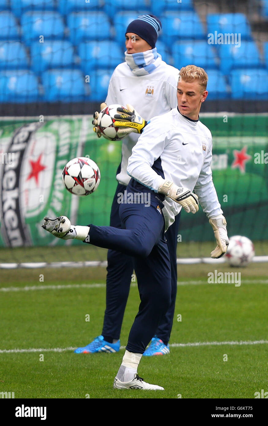 Joe Hart von Manchester City jongliert bei einem Training im Etihad Stadium in Manchester vor Teamkollege Costel Pantilivon mit einem Fußball. Stockfoto