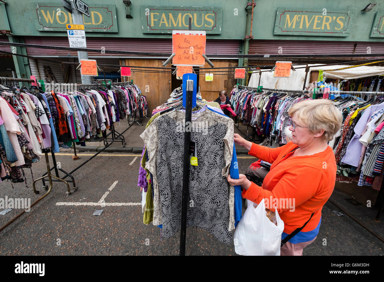 Frau Surfen gebrauchte Kleidung zu Barras Markt in Gallowgate Glasgow, Vereinigtes Königreich Stockfoto