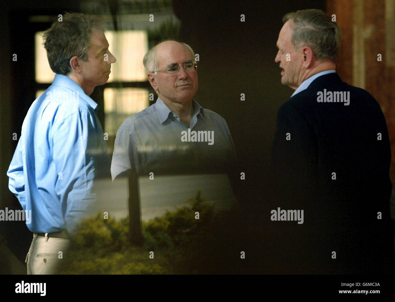 Der britische Premierminister Tony Blair (L) spricht mit dem kanadischen Premierminister Jean Chretien (R) und dem australischen Premierminister John Howard vor dem Beginn eines Treffens der Führer der Commonwealth-Länder in Abuja in Nigeria. Die Anführer sind hinter dem Fenster abgebildet. Stockfoto